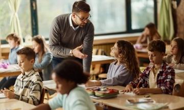 teacher talking to student at desk